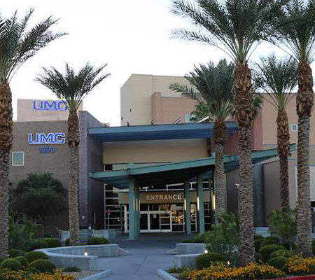 Daytime exterior of the main entrance of University Medical Center of Southern Nevada, flanked by palm trees