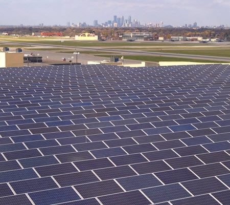 Daytime view of solar panels on the roof of St. Paul International Airport, with the City of Minneapolis on the horizon