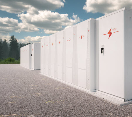 Daytime view of large-scale battery storage enclosures with an evergreen forest in the background